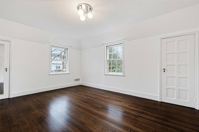 empty room with visible vents, baseboards, and dark wood-type flooring