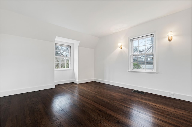 additional living space with lofted ceiling, dark wood-style flooring, visible vents, and baseboards