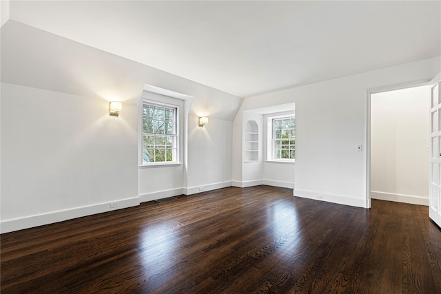 spare room with vaulted ceiling, baseboards, and dark wood finished floors