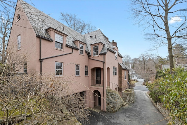 view of property exterior with a chimney, a high end roof, and stucco siding