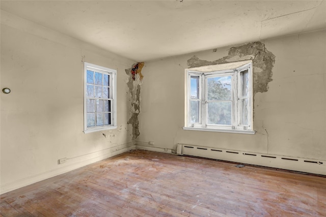 spare room featuring baseboard heating and light hardwood / wood-style floors