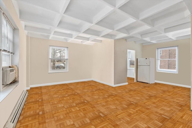 empty room with a baseboard radiator, a wealth of natural light, and baseboards