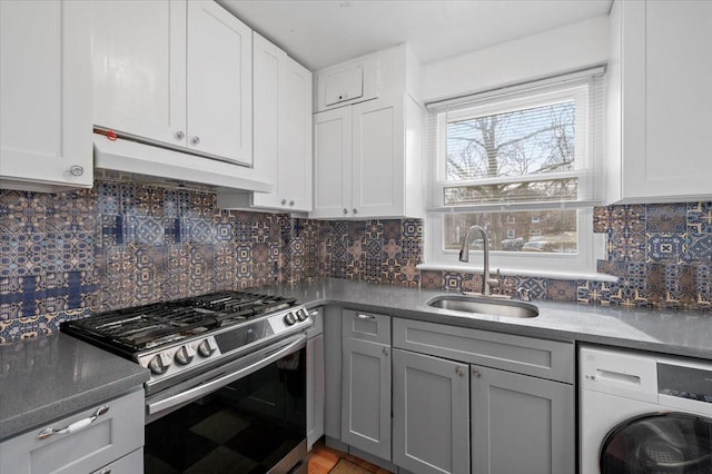 kitchen with white cabinets, washer / clothes dryer, under cabinet range hood, a sink, and gas stove