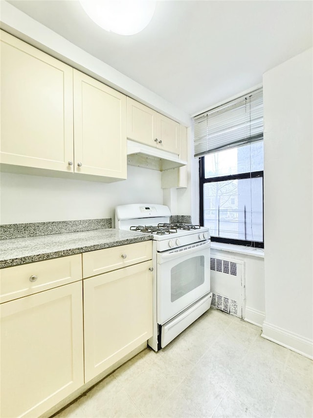 kitchen with radiator, gas range gas stove, and cream cabinetry