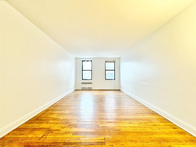 empty room featuring radiator and light hardwood / wood-style flooring