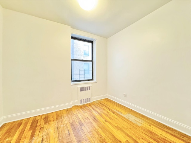 empty room with radiator heating unit and light wood-type flooring