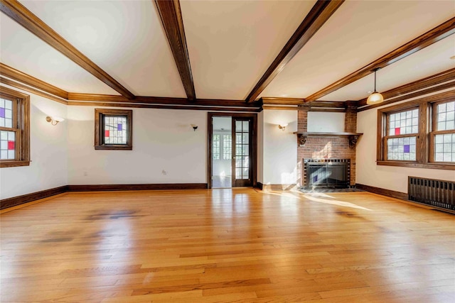 unfurnished living room featuring radiator heating unit, light hardwood / wood-style floors, ornamental molding, a brick fireplace, and beamed ceiling