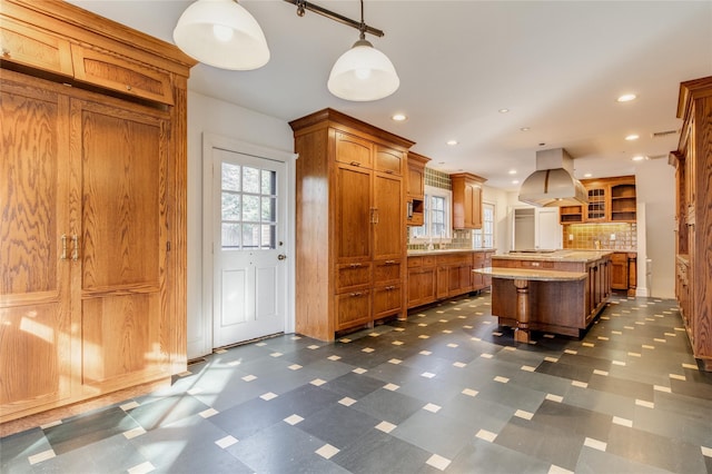 kitchen featuring pendant lighting, a breakfast bar area, a center island, island exhaust hood, and decorative backsplash