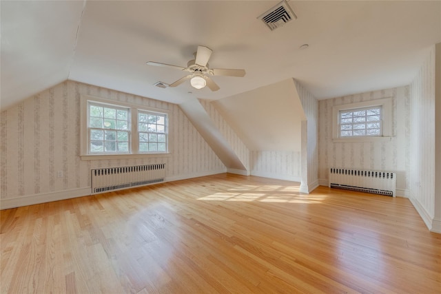 additional living space featuring a wealth of natural light, radiator heating unit, and light wood-type flooring