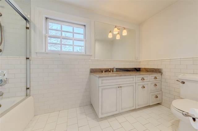 full bathroom with tile patterned floors, toilet, tile walls, vanity, and enclosed tub / shower combo