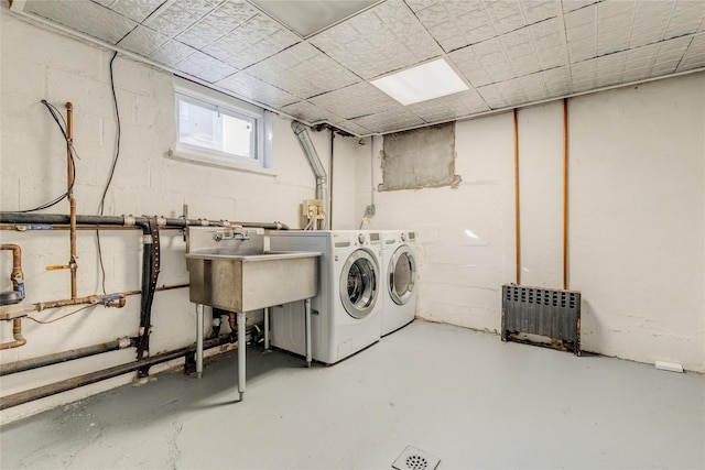 laundry room featuring radiator, washing machine and dryer, and sink