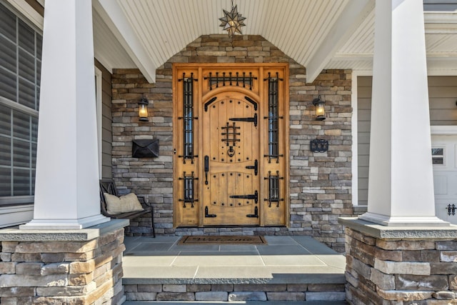 doorway to property featuring a porch and stone siding