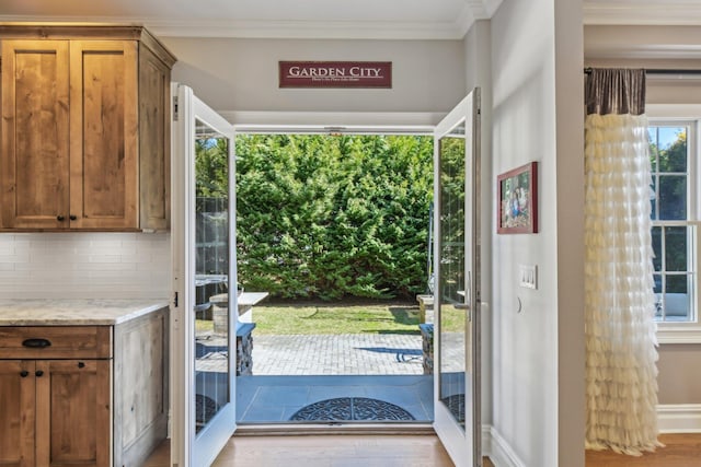 doorway to outside featuring ornamental molding and wood finished floors