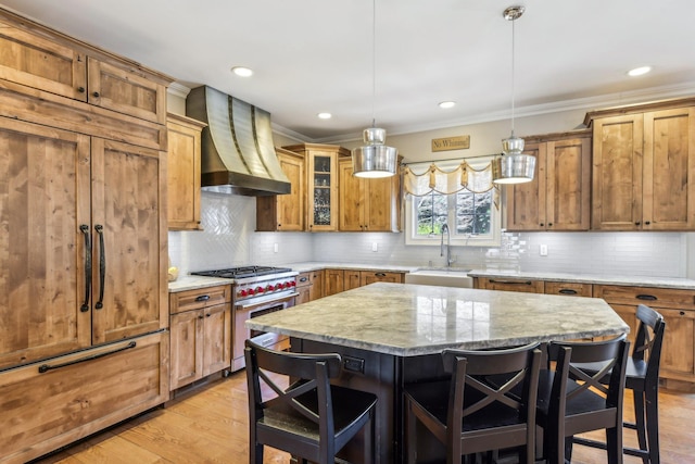 kitchen with wall chimney range hood, a breakfast bar area, stainless steel range, and a sink