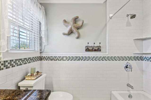 bathroom with washtub / shower combination, wainscoting, tile walls, and toilet