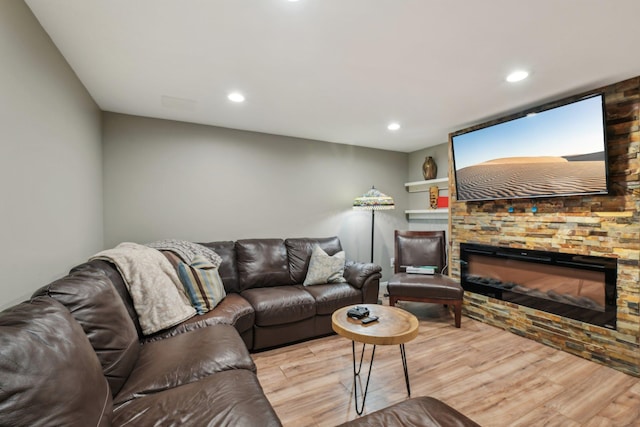 living area featuring recessed lighting, a stone fireplace, and wood finished floors