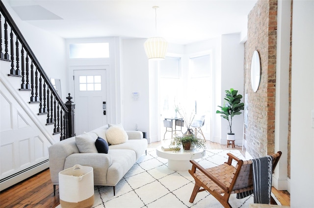 living room featuring a baseboard radiator, brick wall, and light hardwood / wood-style floors