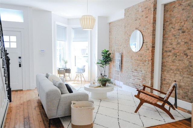 living room featuring brick wall, light hardwood / wood-style flooring, and a baseboard heating unit