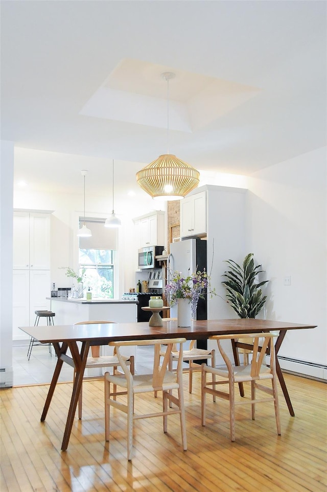 kitchen with decorative light fixtures, white cabinets, light hardwood / wood-style floors, a tray ceiling, and stainless steel appliances