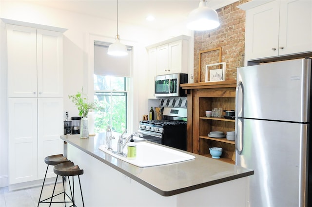 kitchen with stainless steel appliances, white cabinetry, a breakfast bar area, and pendant lighting