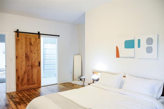 bedroom featuring wood-type flooring, a barn door, and connected bathroom