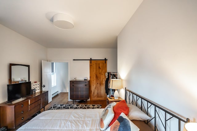 bedroom featuring a barn door, dark hardwood / wood-style floors, and baseboard heating