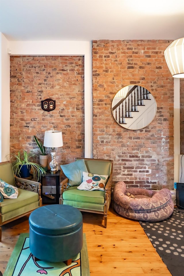 sitting room featuring brick wall and hardwood / wood-style floors