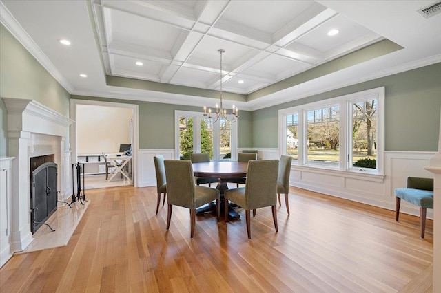 dining area featuring light hardwood / wood-style floors, a high end fireplace, coffered ceiling, and beam ceiling