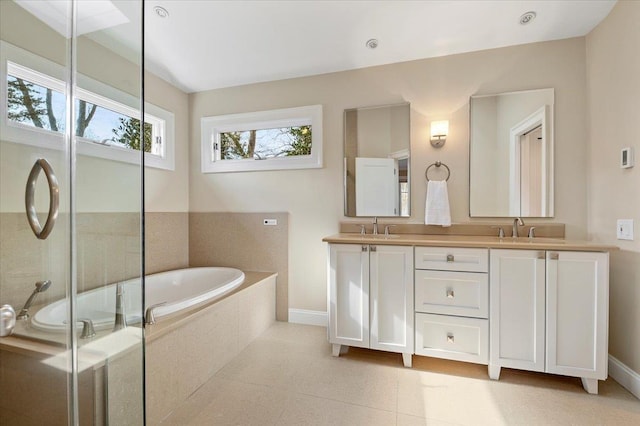 bathroom with tiled bath, tile patterned floors, and vanity