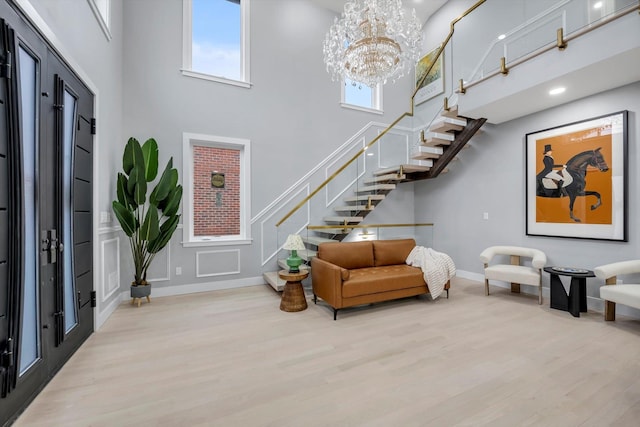 entryway featuring a towering ceiling, a chandelier, and light hardwood / wood-style flooring