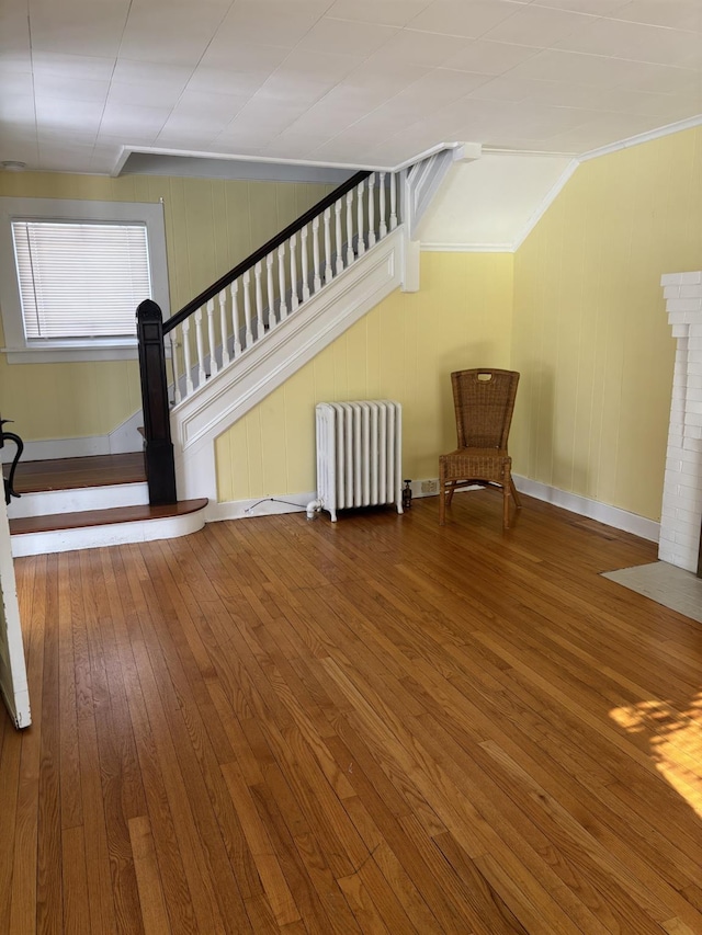 interior space with hardwood / wood-style flooring, ornamental molding, and radiator