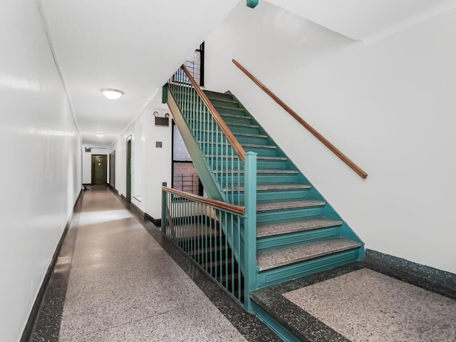 stairway featuring speckled floor and baseboards