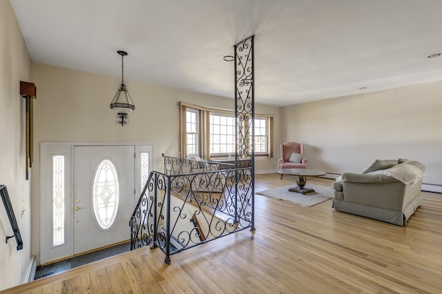 foyer entrance with light wood-style flooring, baseboards, and baseboard heating