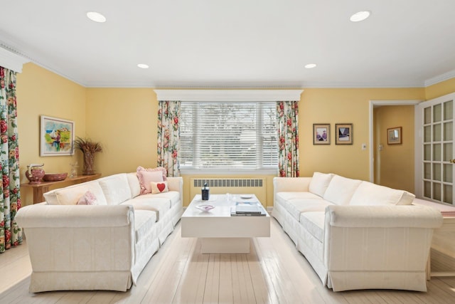 living room with crown molding, radiator heating unit, and light hardwood / wood-style flooring