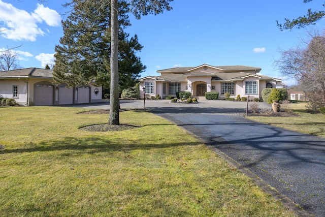 mediterranean / spanish house with a garage, aphalt driveway, a front yard, and stucco siding