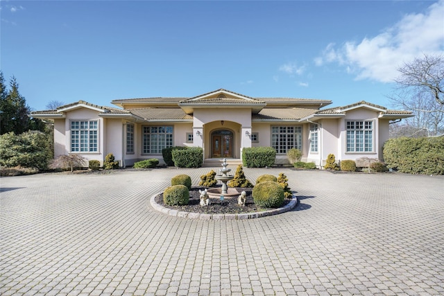 view of front of house with a tile roof, curved driveway, and stucco siding