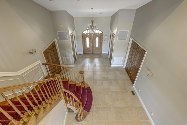 entryway with an inviting chandelier, visible vents, stairs, and high vaulted ceiling