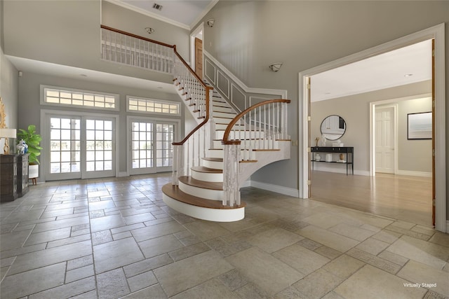 foyer with baseboards, a high ceiling, stairway, and stone tile floors