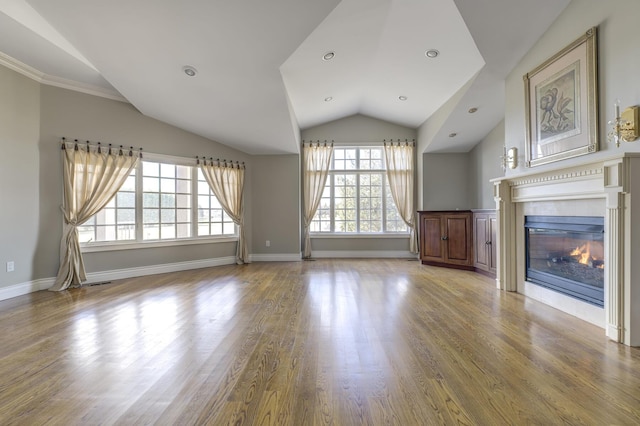 unfurnished living room with baseboards, a glass covered fireplace, wood finished floors, vaulted ceiling, and recessed lighting