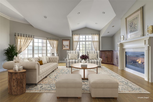 living area featuring lofted ceiling, recessed lighting, wood finished floors, and a glass covered fireplace