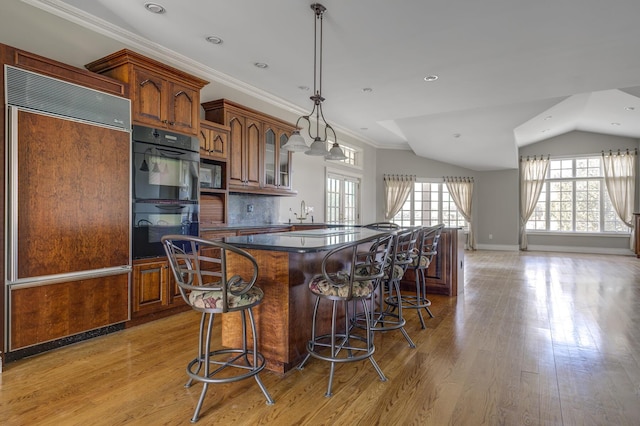 kitchen featuring built in appliances, light wood-style floors, dark countertops, and a center island