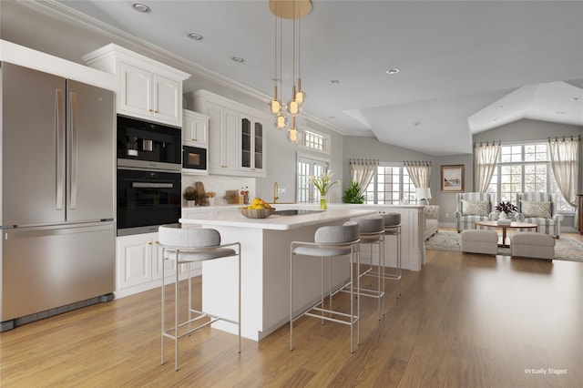 kitchen with black microwave, white cabinets, a breakfast bar area, and freestanding refrigerator