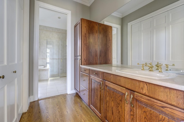 bathroom with ornamental molding, tiled shower, wood finished floors, and vanity