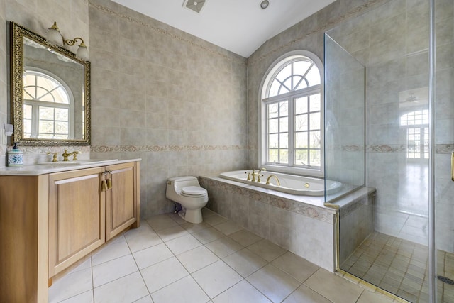 bathroom with toilet, vanity, tile walls, a bath, and tile patterned floors