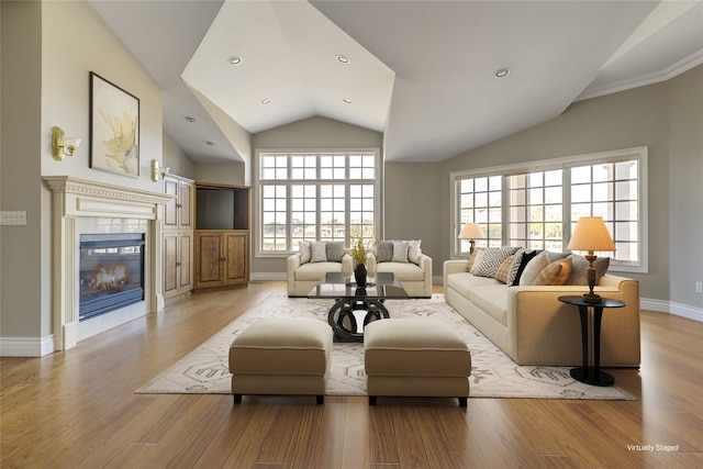 living area with lofted ceiling, a fireplace, wood finished floors, and baseboards