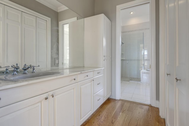 full bath with ornamental molding, a tile shower, wood finished floors, and vanity