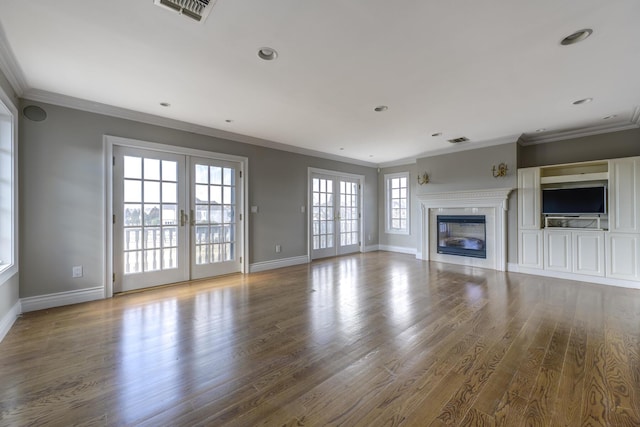 unfurnished living room with french doors, ornamental molding, a glass covered fireplace, wood finished floors, and baseboards