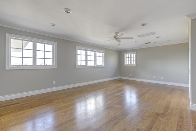 empty room with ceiling fan, wood finished floors, visible vents, baseboards, and crown molding