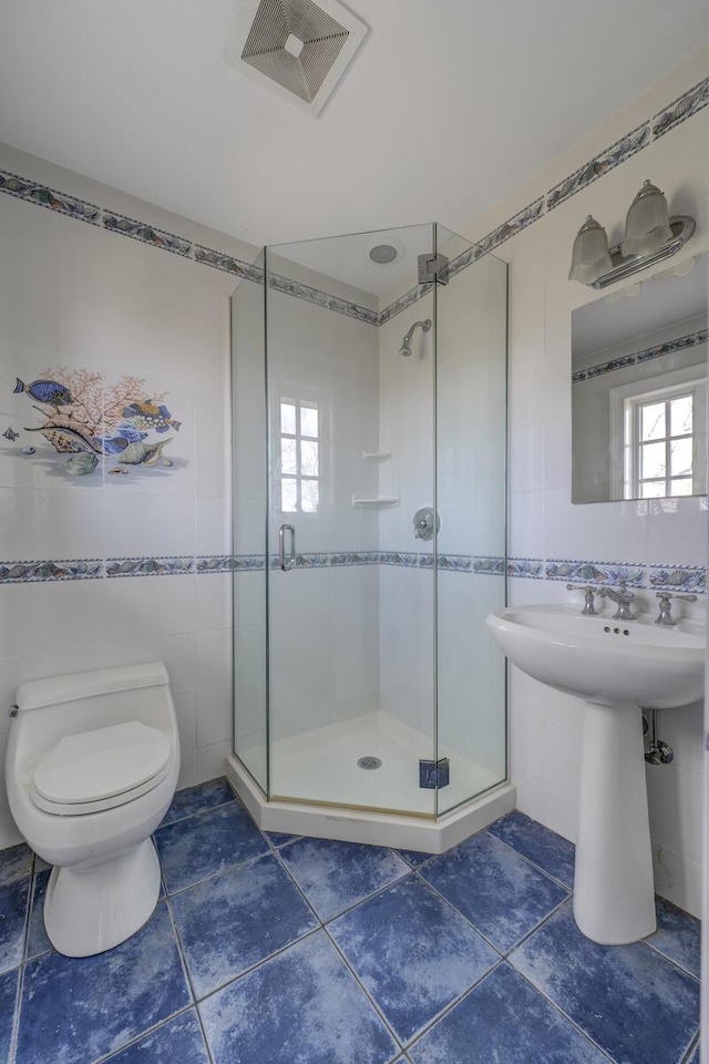 bathroom with tile walls, visible vents, toilet, a shower stall, and tile patterned floors