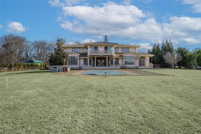 rear view of property with a patio, a balcony, fence, a lawn, and stucco siding